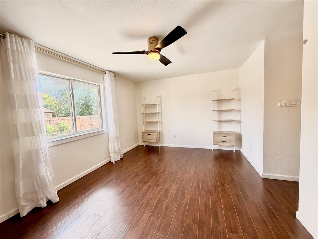 Wood-finish flooring, dual built-in wall shelving units with integrated storage drawers, and a ceiling fan with integrated lighting
