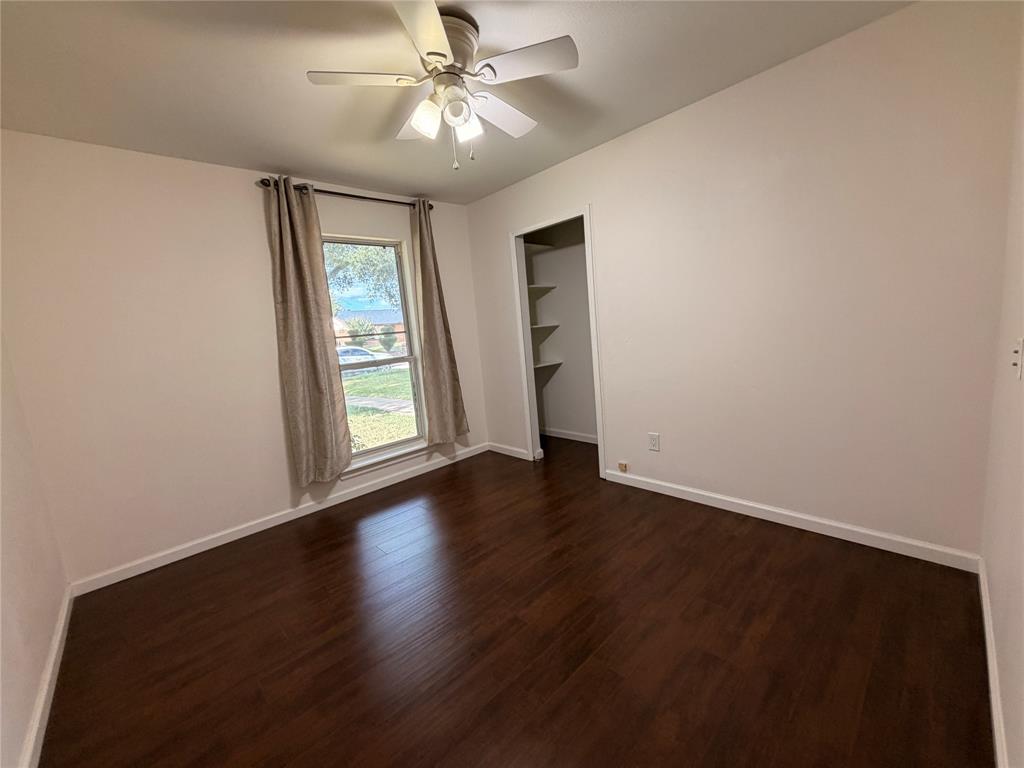 Interior space featuring wood-finish flooring, a ceiling fan with light fixture, a single window, and a built-in closet with shelving
