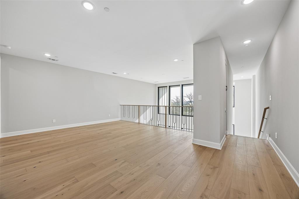 Open-concept space featuring wood-finish flooring, recessed lighting, and a metal railing