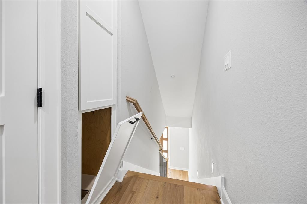 Built-in storage cabinet with recessed panel doors, wood-finish flooring, and wall-mounted handrail