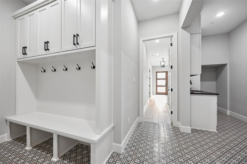 Built-in mudroom cabinetry with shaker-style doors, integrated bench seating, matte black hardware, and patterned tile flooring