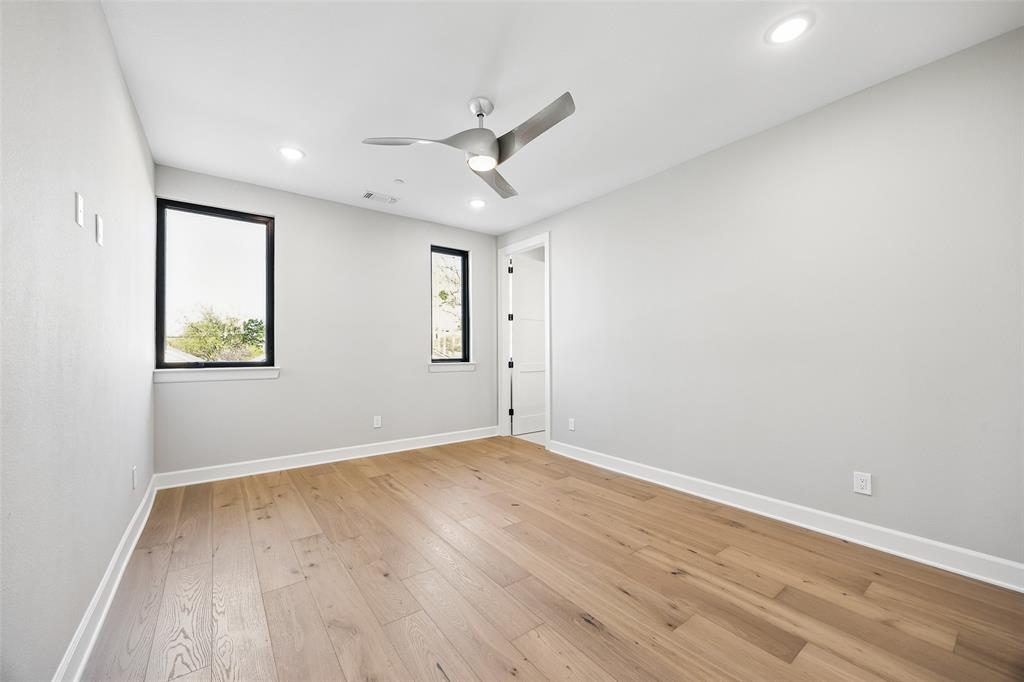 Room featuring wood-finish flooring, recessed lighting, a modern ceiling fan, and windows with black frames
