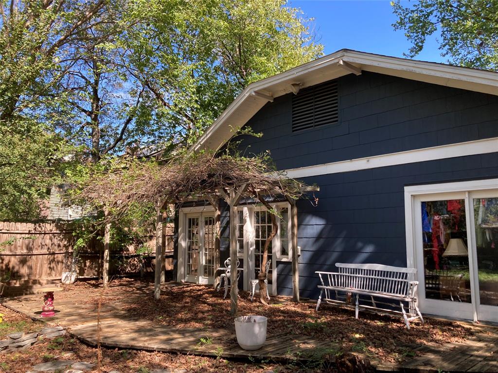 Rear exterior featuring dark-toned shake siding, a wooden pergola, sliding glass doors, and a wood-decking patio
