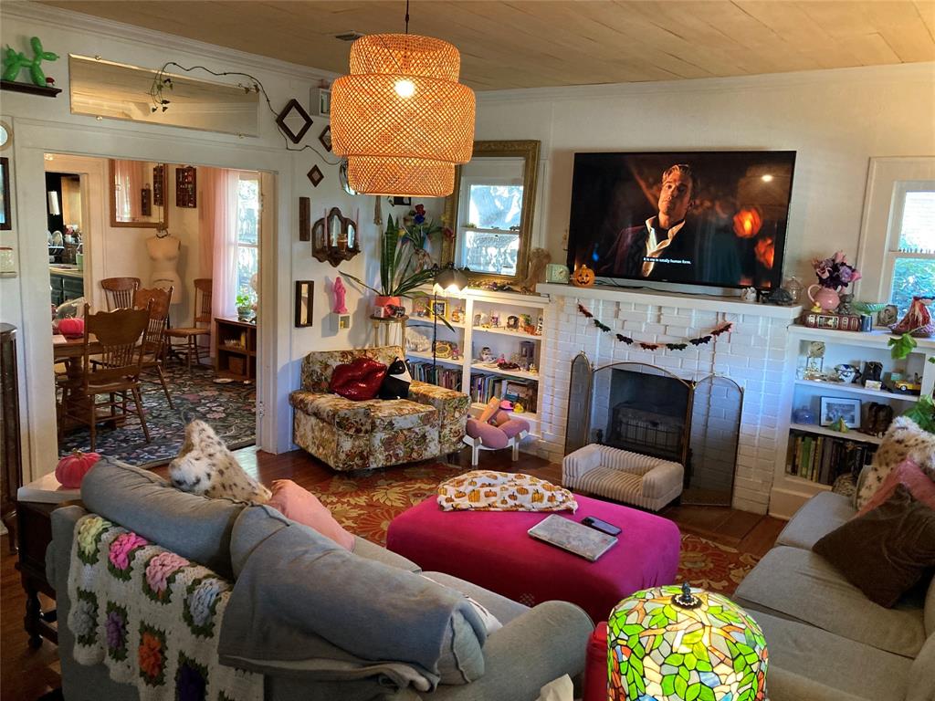 Living space featuring a brick fireplace with a mantel, built-in shelving, wood-plank ceiling, and a woven pendant light fixture
