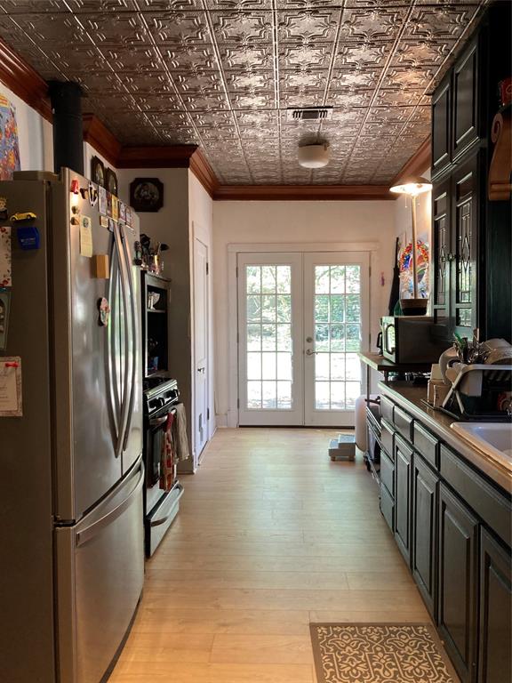Kitchen featuring a decorative pressed-tin ceiling, wood-finish flooring, dark-finish cabinetry, and French-style glass pane doors