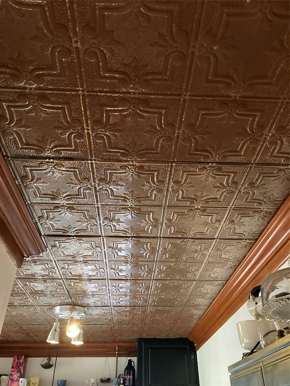 Metallic-finish pressed tin ceiling featuring ornate geometric tile patterns and a polished crown molding border