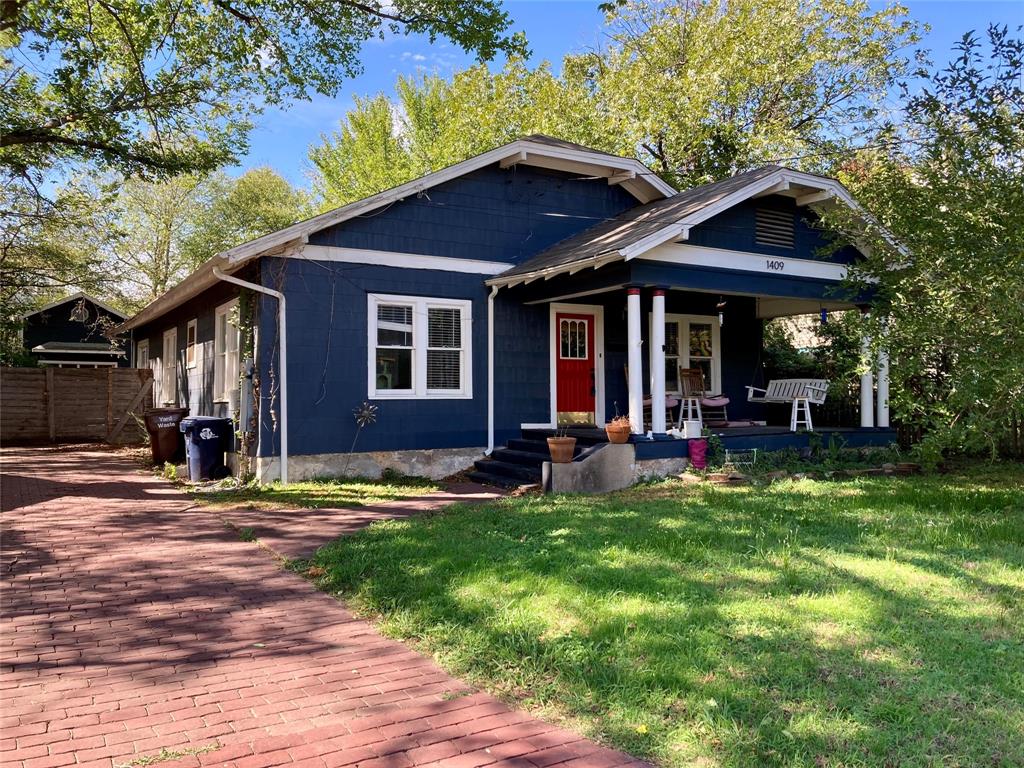 Craftsman-style exterior featuring shake siding, a covered front porch with tapered columns, and a brick driveway