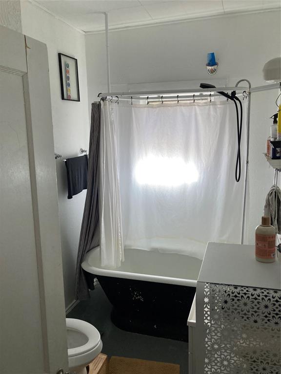 Clawfoot tub featuring a black exterior finish, white interior, and wall-mounted shower hardware
