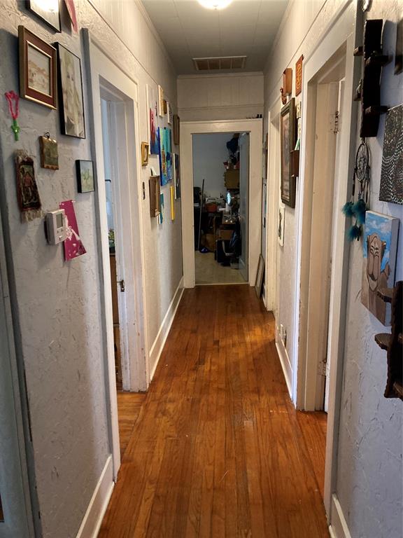 Hallway featuring wood-finish flooring, textured wall surfaces, and classic door casing trim