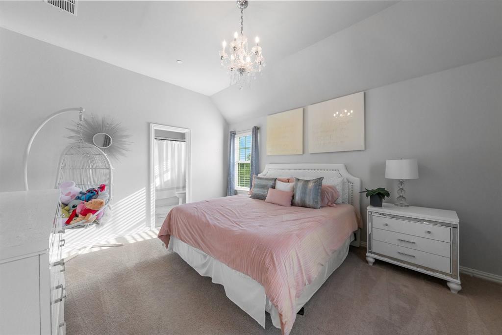 Vaulted ceilings, crystal chandelier, neutral wall color, and window with natural light