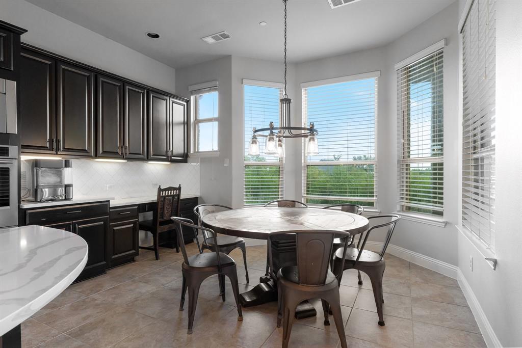 Kitchen featuring dark finish cabinetry, built-in desk, stone-surface countertops, tile flooring, and a bay window configuration