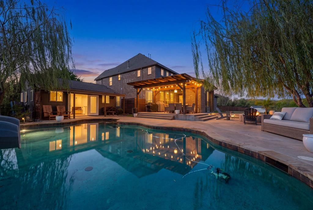 Backyard oasis featuring an in-ground pool, expansive concrete patio, wooden pergola, and mature trees