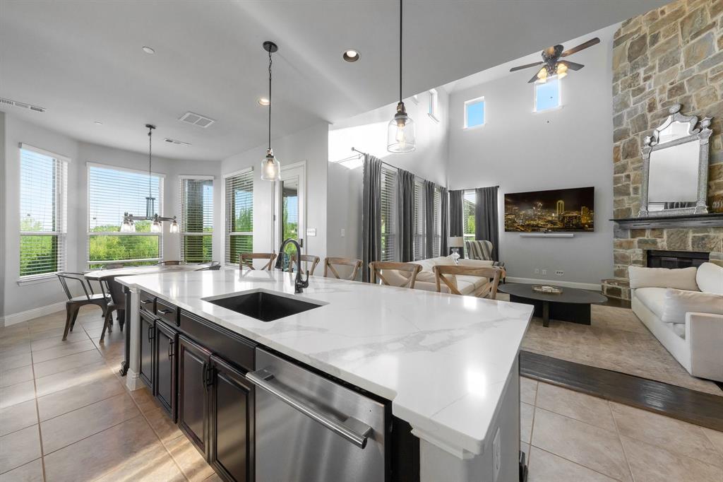 Kitchen island featuring a stone-surface countertop, under-mount sink, and dark cabinetry