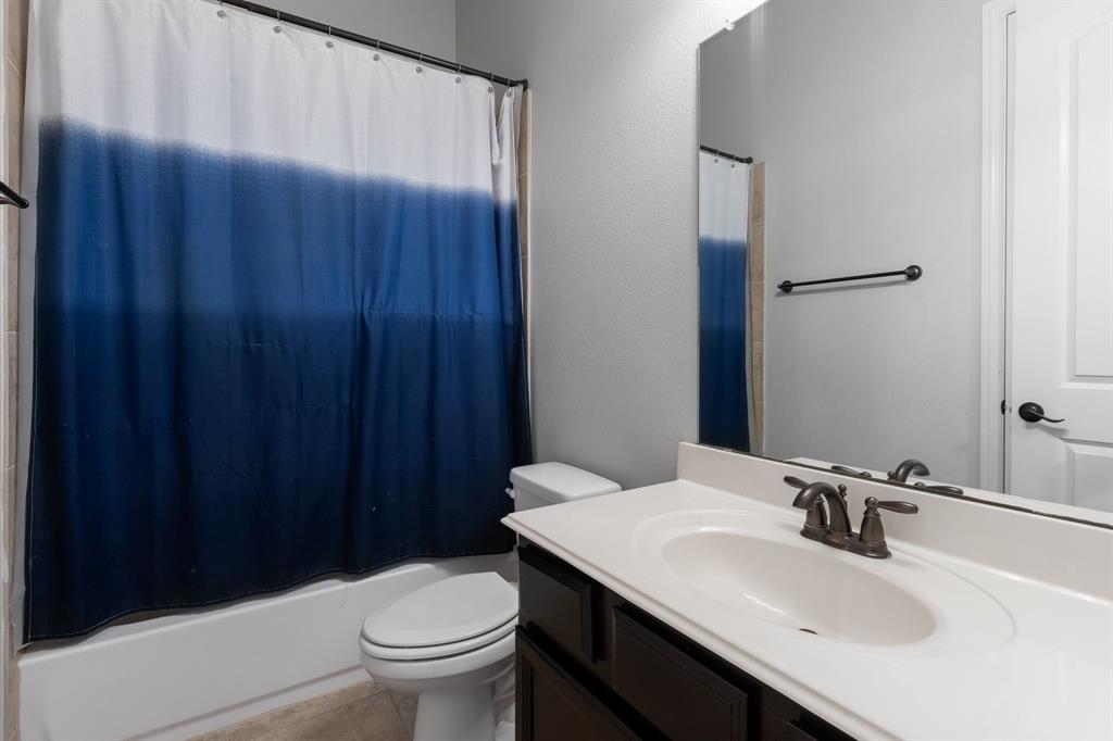 Bathroom featuring a vanity with a dark-finish base, integrated sink, and an expansive wall-mounted mirror with a matching dark-finish towel bar