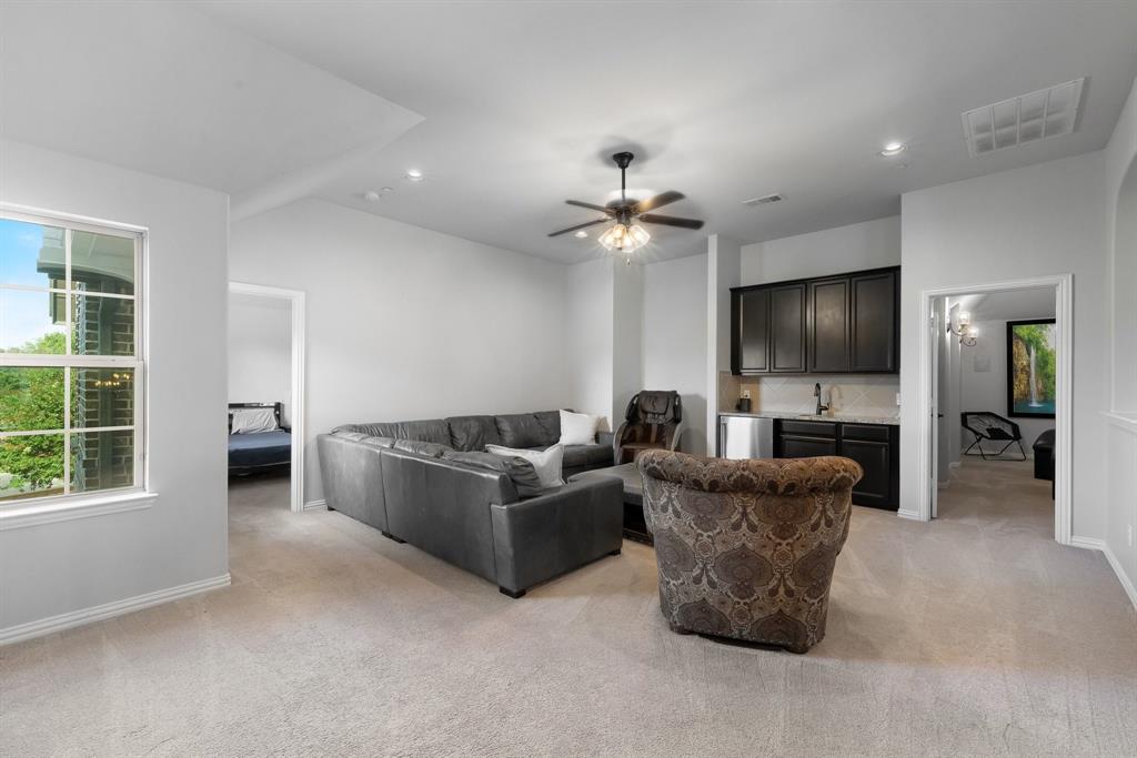 2nd living area upstairs. Wet bar featuring dark-toned cabinetry, light-toned stone-finish countertop, stainless steel sink, and recessed lighting, accented by a ceiling fan
