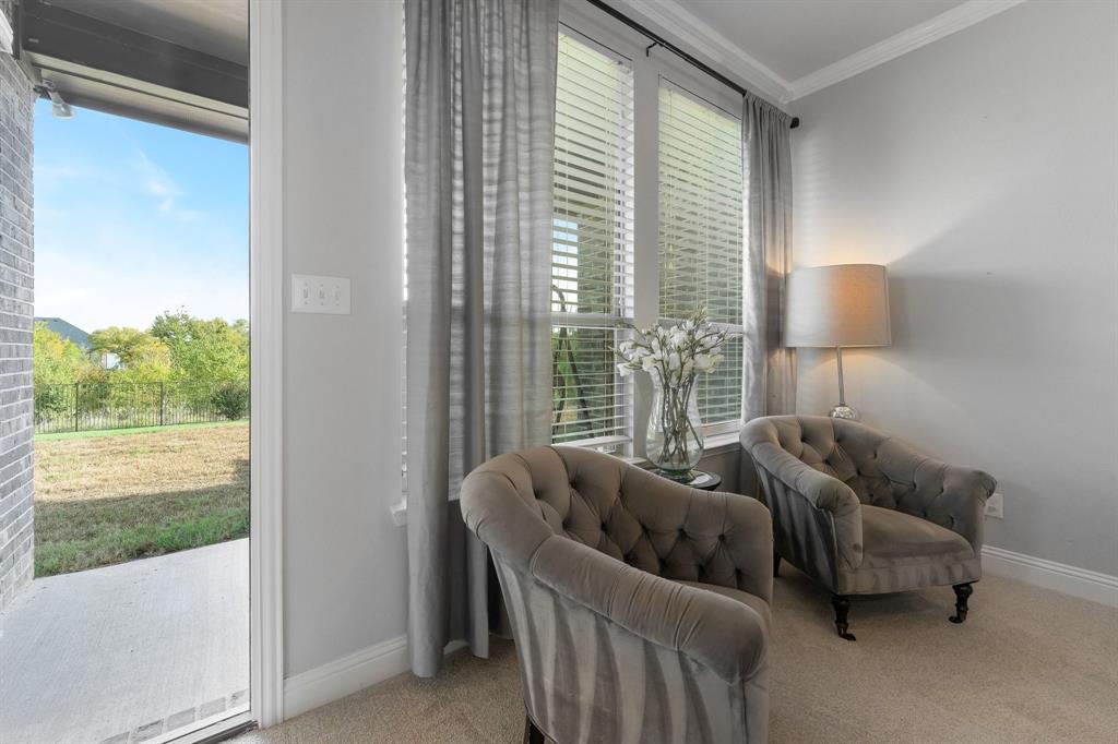 Large windows with horizontal blinds, neutral wall color, and a door providing exterior access to a concrete patio