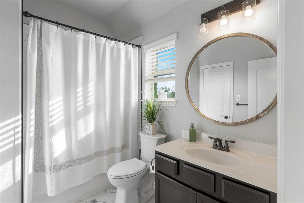 Completely renovated bathroom!! Dark-toned vanity with a light-colored countertop, integrated oval sink, circular wall-mounted mirror, and three-bulb vanity light fixture and luxury tile.