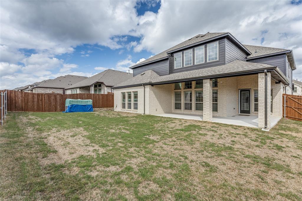 Two-story exterior featuring light-toned brick masonry, horizontal siding, a covered concrete patio, and wood privacy fencing