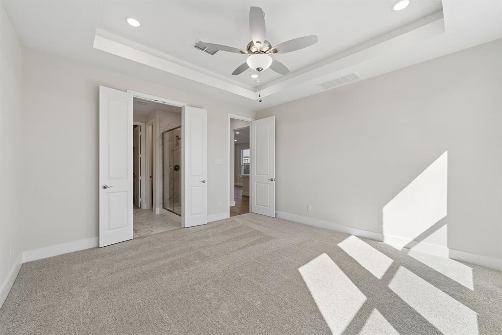 Tray ceiling featuring an integrated multi-blade ceiling fan with light kit, recessed lighting, neutral carpeting, and solid-core interior doors
