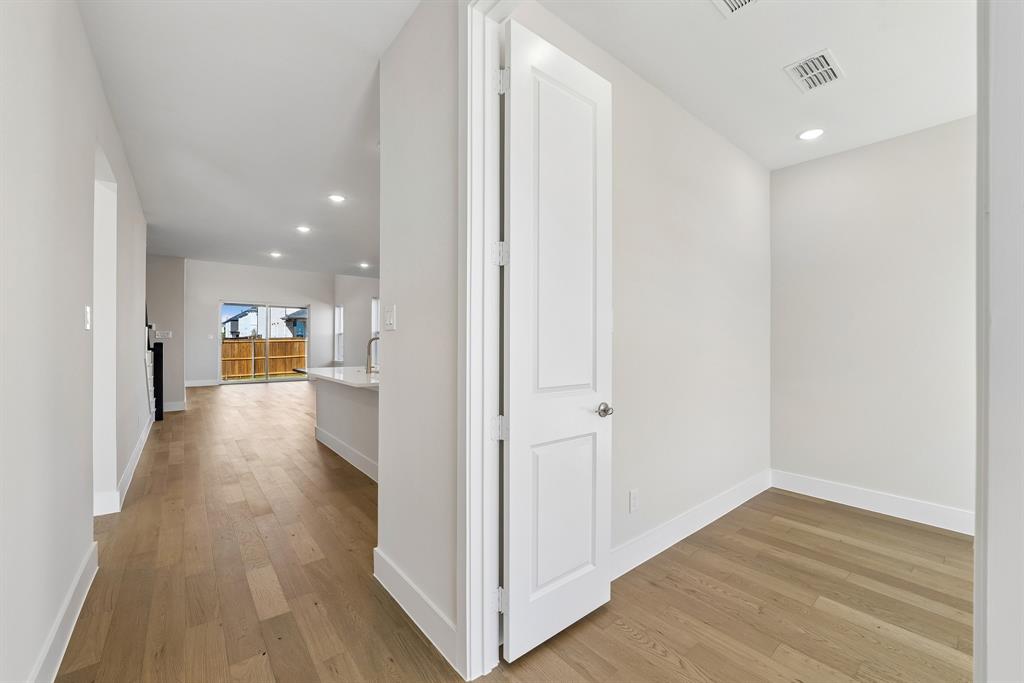 Neutral-toned interior featuring wood-finish flooring, recessed lighting, and a crisp white panel door