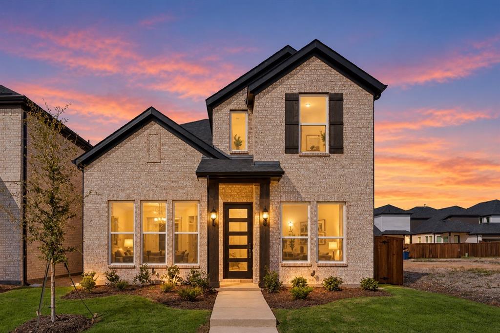 Two-story brick exterior with dark-trimmed gables, multi-pane front entry door, and large-format rectangular windows