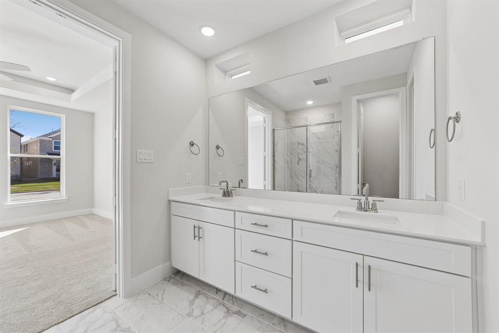 Double vanity featuring white cabinetry, stone-finish countertops, undermount sinks, and a full-width mirror with clerestory windows