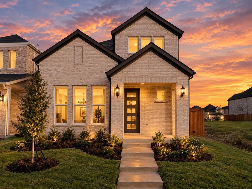 Brick exterior with multi-gabled roofline, concrete walkway, and entryway featuring a multi-pane glass door and mounted sconce lighting