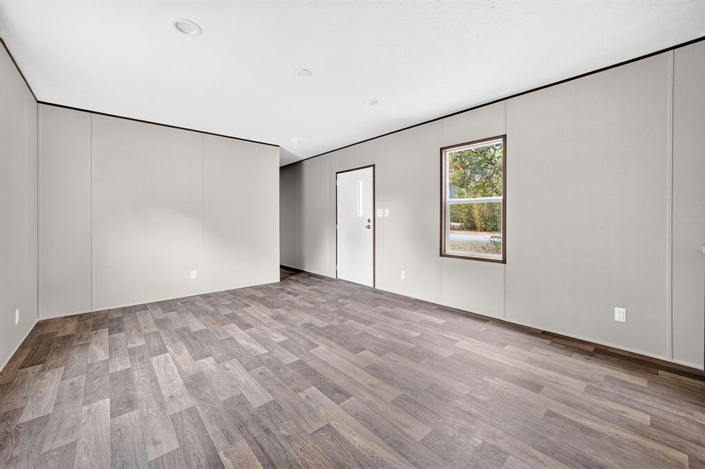 Neutral-toned interior room featuring wood-finish flooring, recessed lighting, and a single-pane window with dark trim
