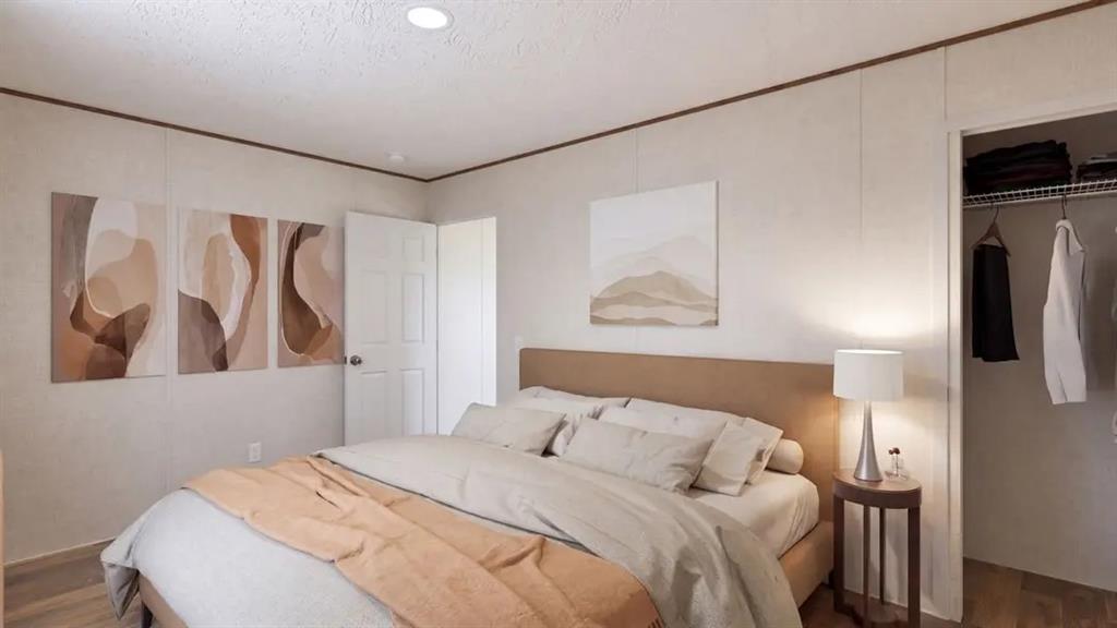 Bedroom featuring neutral-toned panel walls, wood-finish flooring, recessed ceiling lighting, and a reach-in closet with integrated shelving