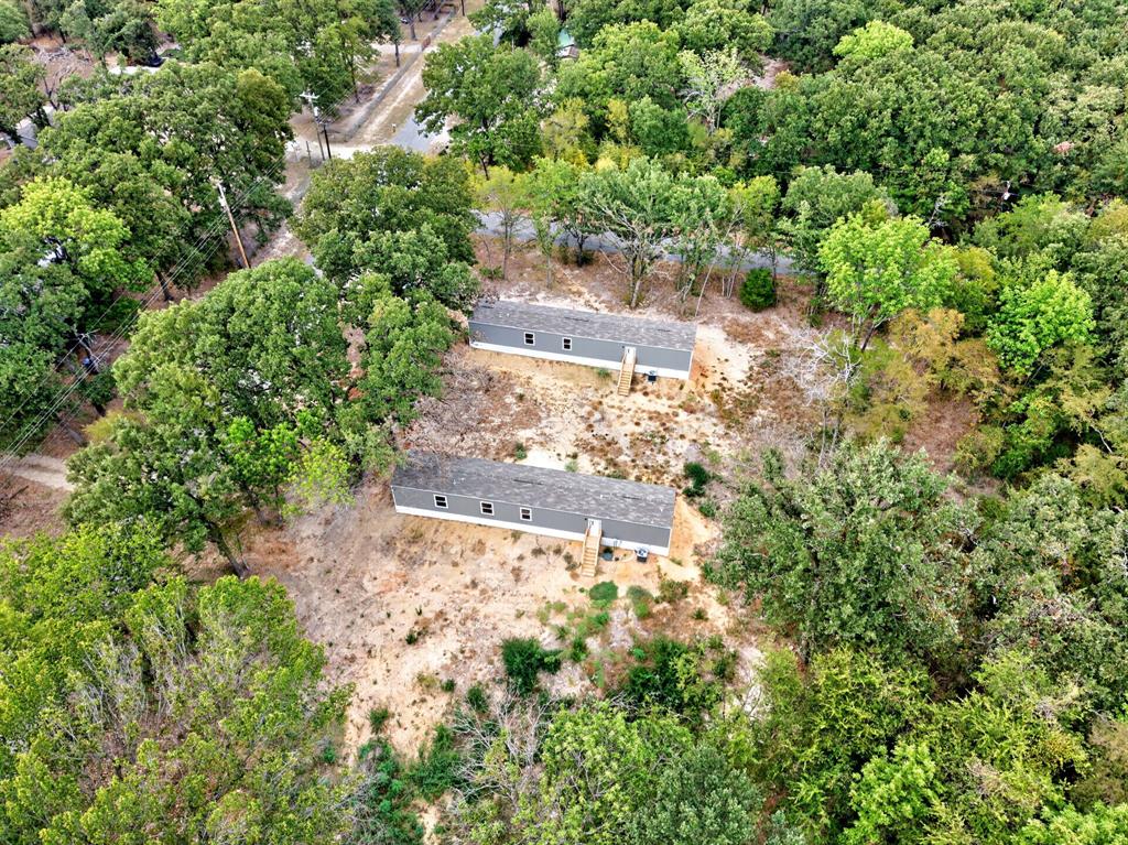 Aerial perspective of two structures on a wooded lot featuring gray siding, pitched roofs, and exterior staircase entryways