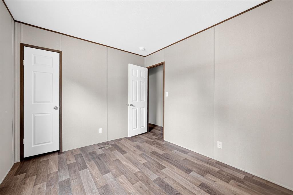 Interior space featuring wood-finish flooring, white six-panel doors, and neutral wall surfaces
