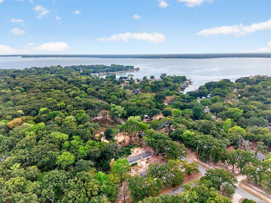Aerial perspective of a waterfront property featuring extensive mature tree coverage, a natural shoreline, and proximity to open water