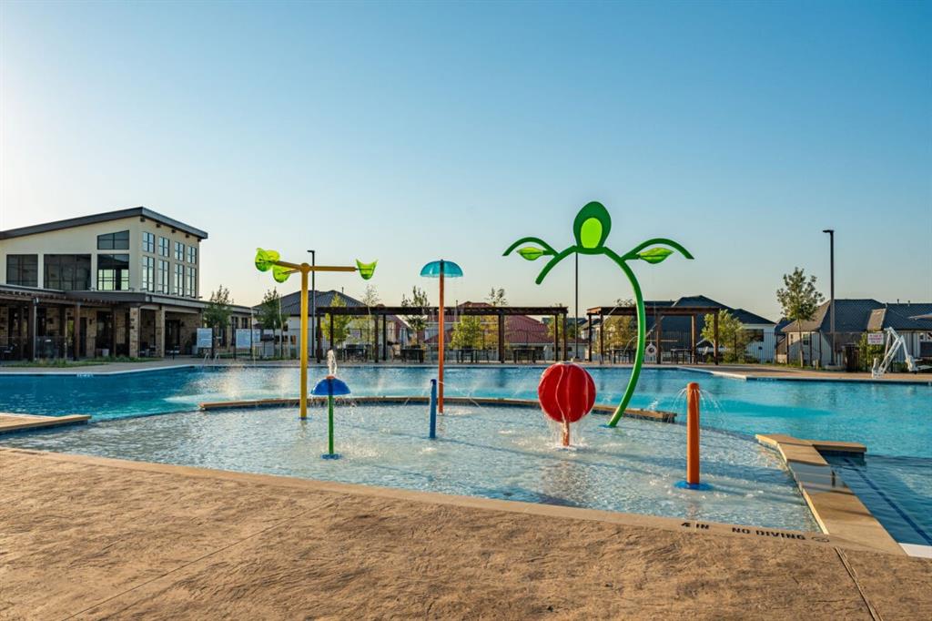LEXINGTON Community Swimming pool with a zero-entry splash pad featuring colorful water spray fixtures and a textured concrete deck LEXINGTON Community Swimming pool with a zero-entry splash pad featuring colorful water spray fixtures and a textured concrete deck