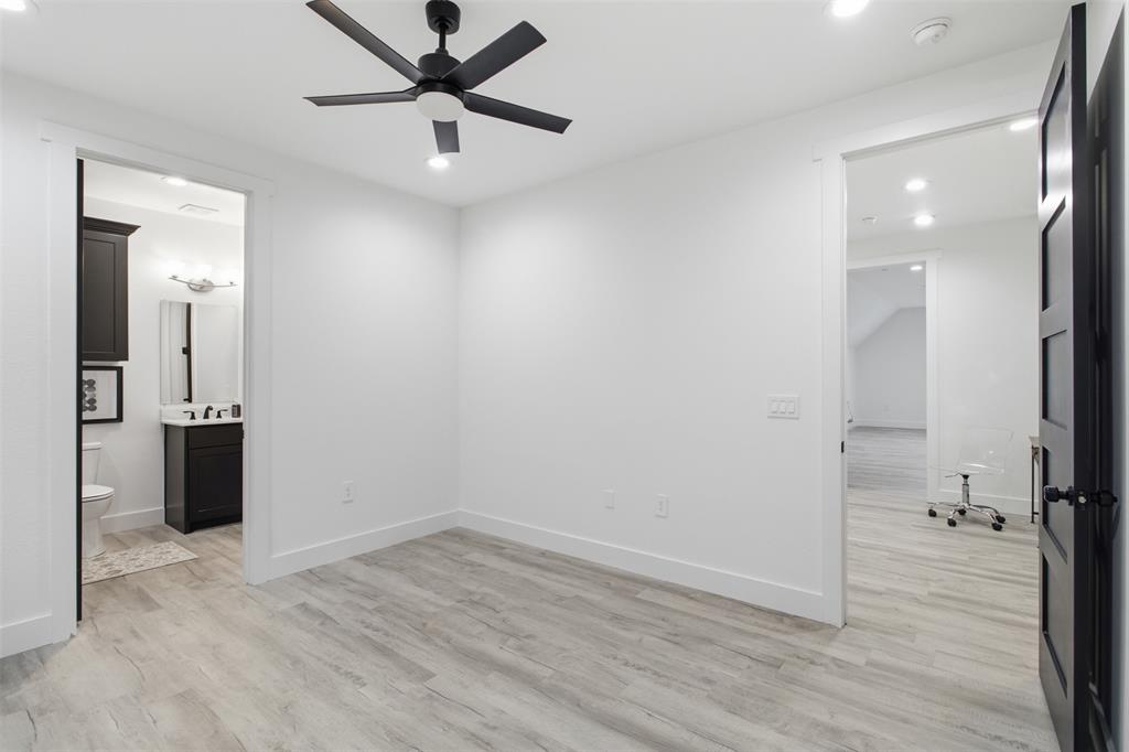 Interior space featuring wood-finish flooring, a five-blade matte black ceiling fan, recessed lighting, and contrasting dark-finished doors