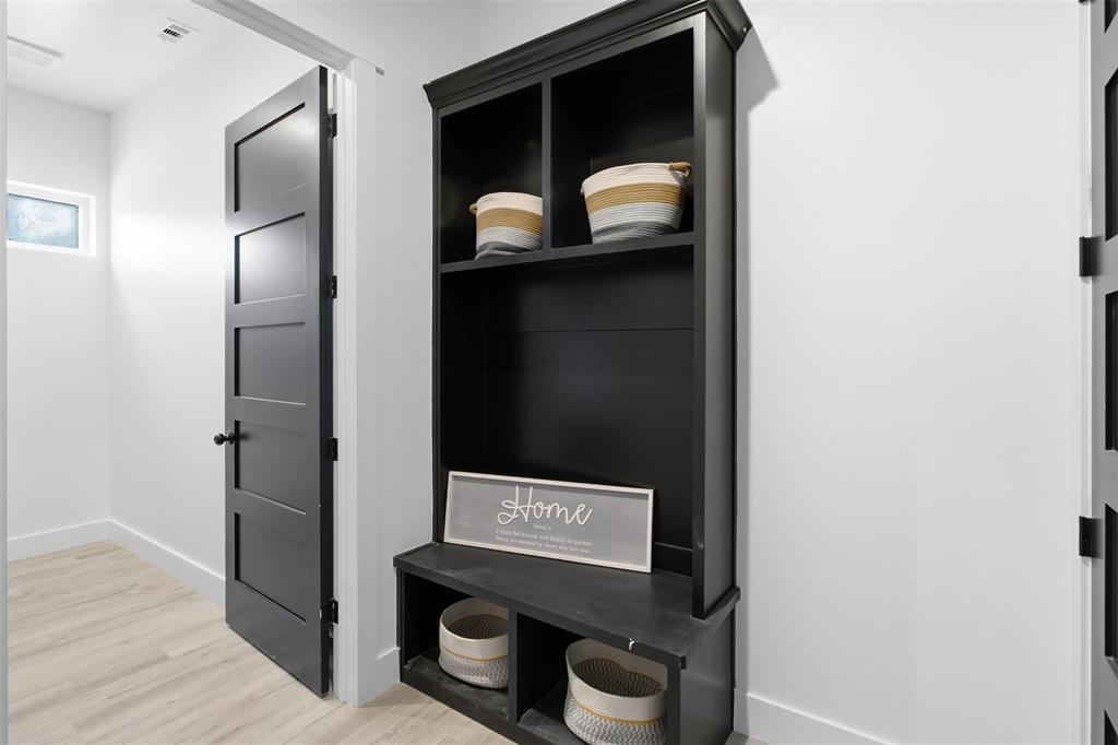 Built-in black hall tree with integrated bench seating, wood-finish flooring, and solid-core four-panel interior doors