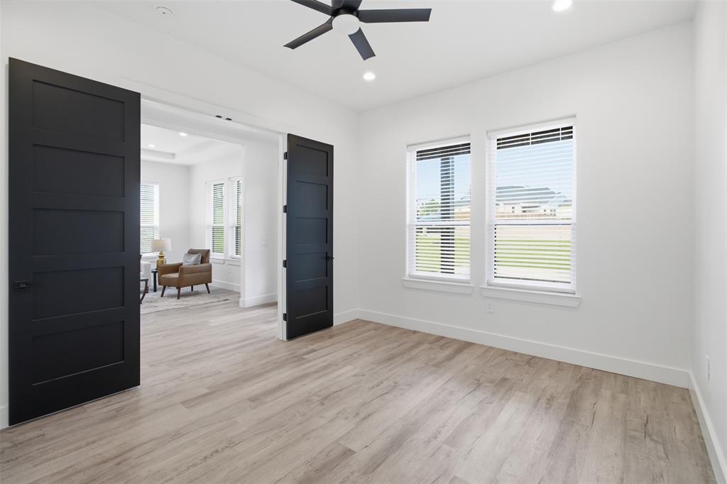 Room featuring wood-finish flooring, matte black shaker-style double doors, recessed lighting, and a modern ceiling fan