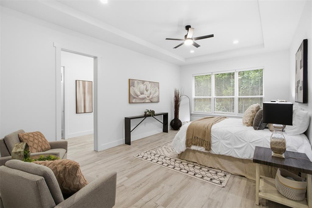 Bedroom featuring wood-finish flooring, a recessed tray ceiling, and a central ceiling fan with integrated lighting