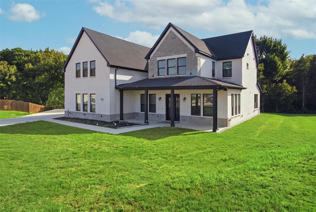 Two-story residence featuring a painted brick and stone facade, a covered front porch, dark-framed multi-pane windows, and a multi-gabled roofline