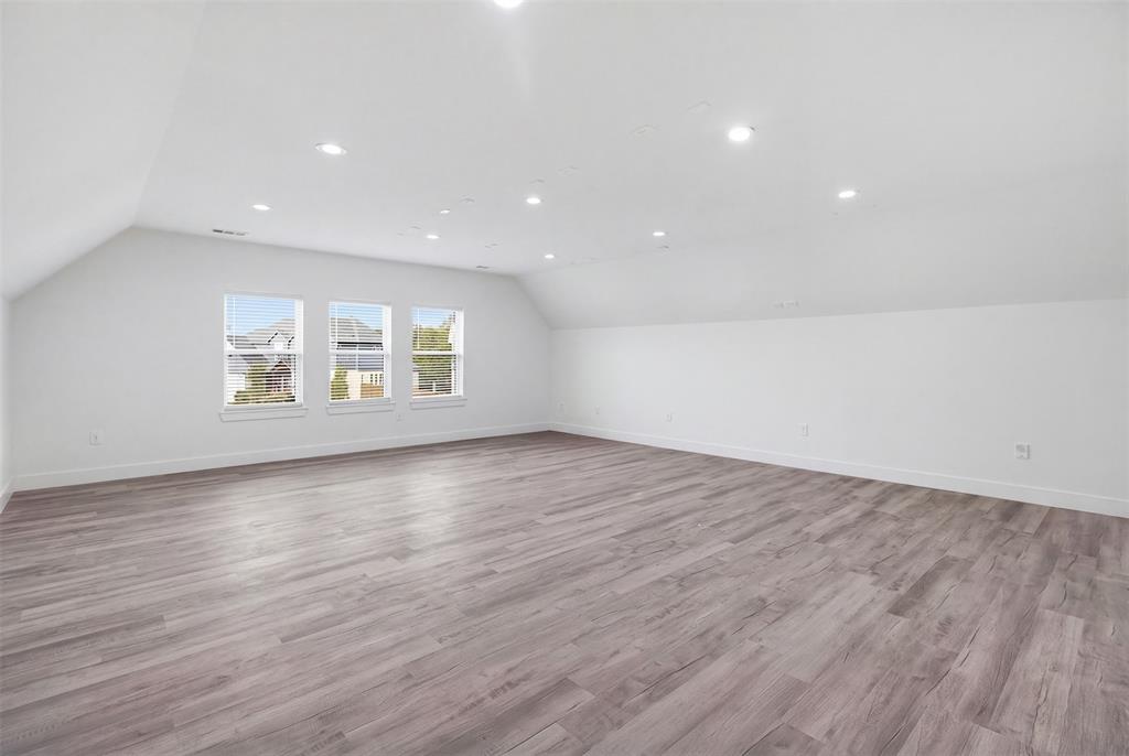 Expansive media room featuring wood-finish flooring, vaulted ceilings, and recessed lighting