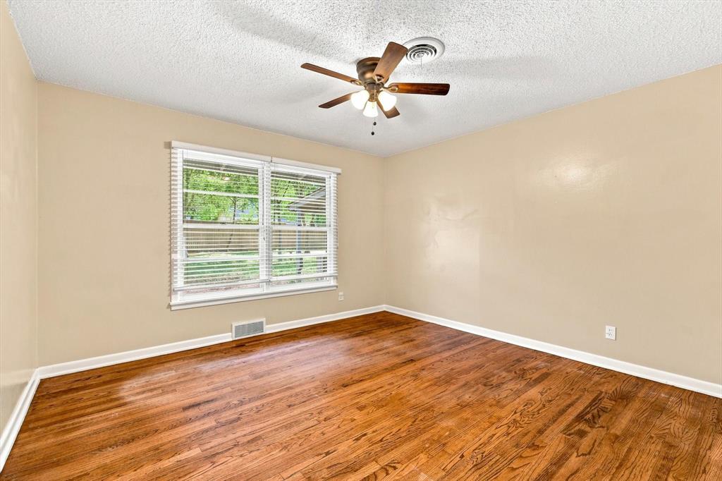 Room featuring wood-finish flooring, a ceiling fan with integrated lighting, and a window with horizontal blinds