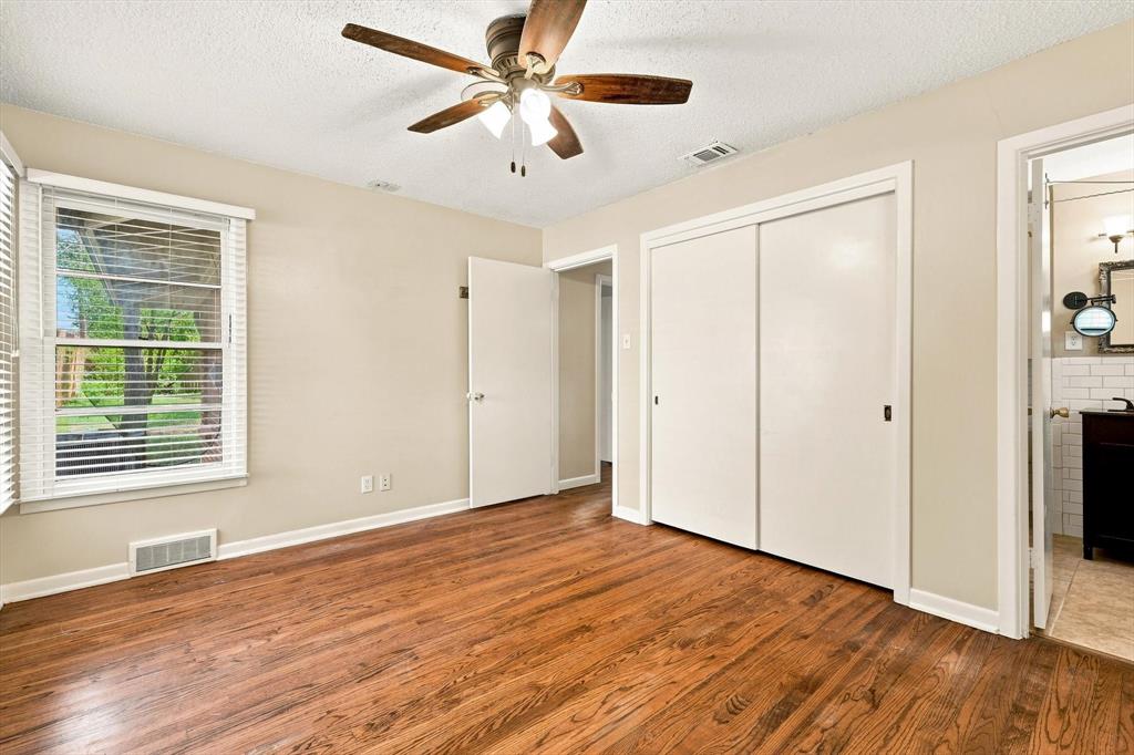 Room featuring wood-finish flooring, a multi-blade ceiling fan with integrated lighting, dual-panel sliding closet doors, and a window with horizontal blinds