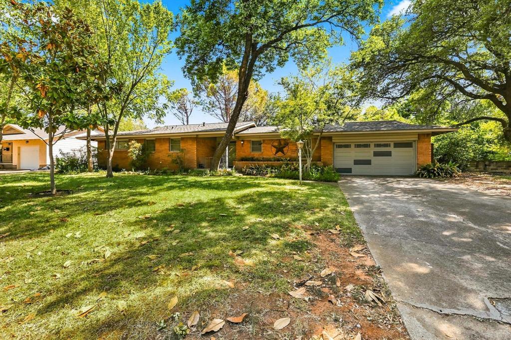 Single-story brick exterior featuring a multi-car garage, concrete driveway, and mature landscaping