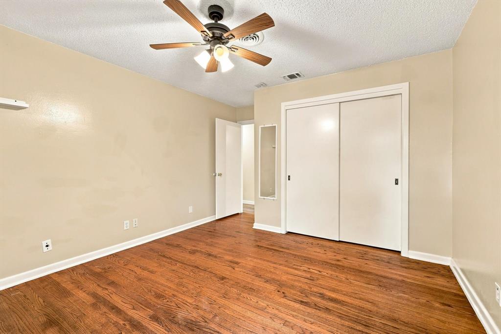 Wood-finish flooring, ceiling fan with integrated lighting, and closet with sliding doors