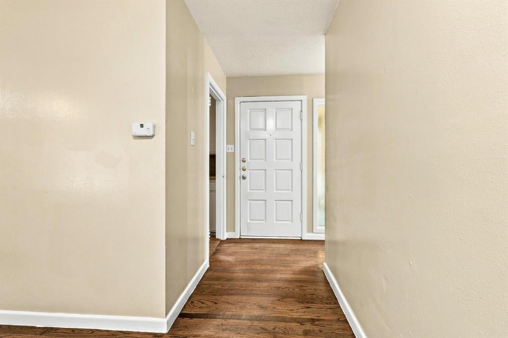 Entryway featuring wood-finish flooring, a white paneled door with hardware, and a side-light window panel