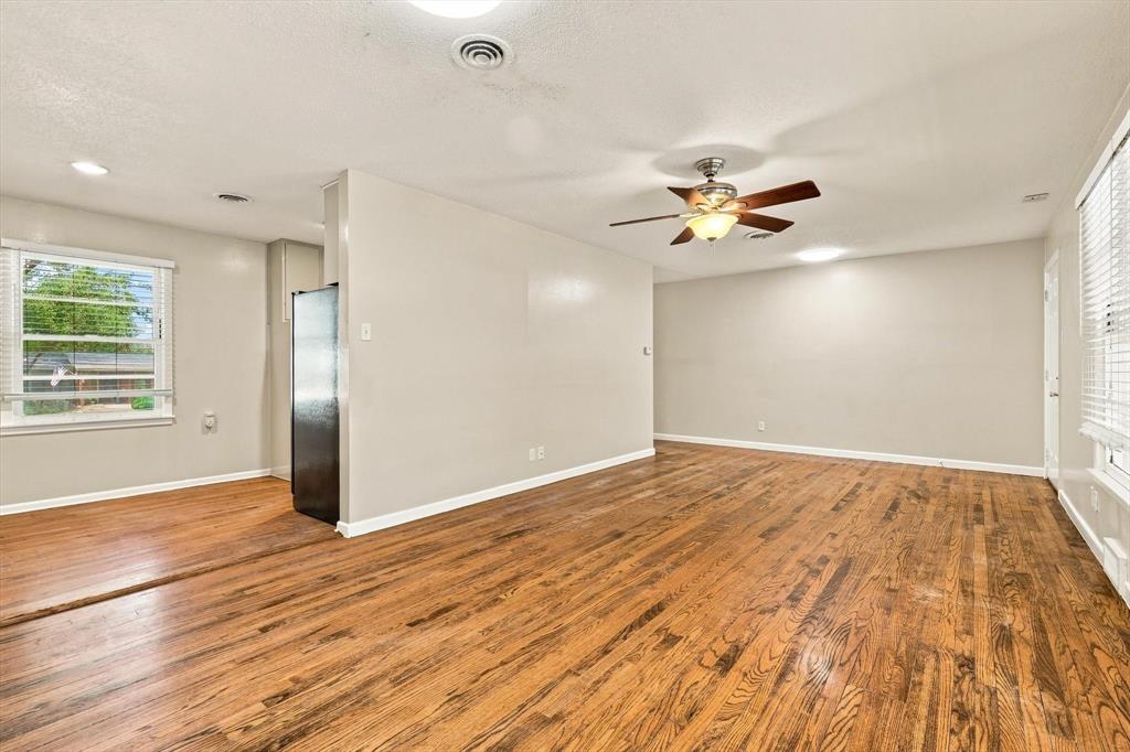 Interior space featuring wood-finish flooring, a ceiling fan with integrated lighting, and multiple windows with horizontal blinds