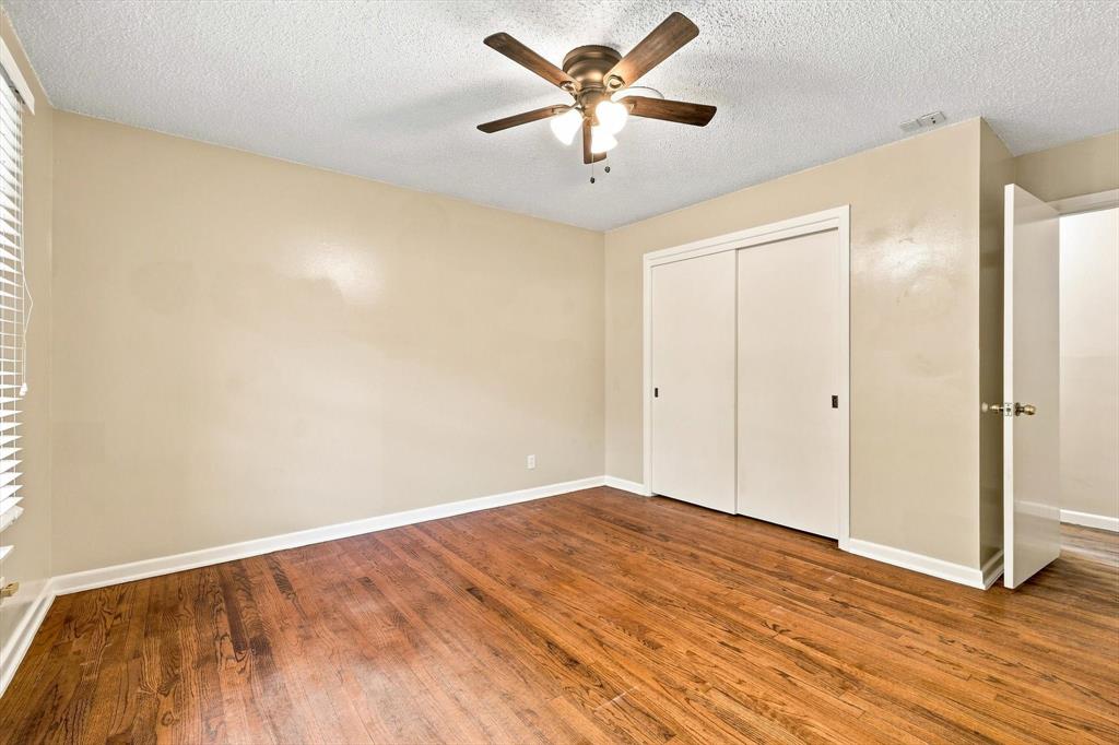 Room featuring wood-finish flooring, a ceiling fan with integrated lighting, and a sliding-door closet