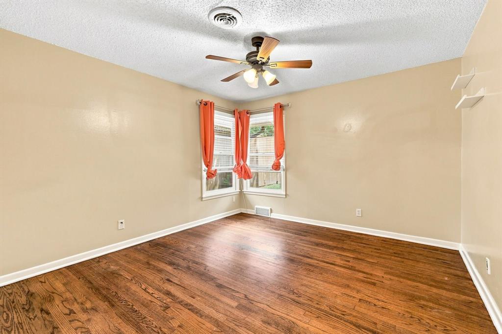 Room featuring wood-finish flooring, corner windows, a ceiling fan with integrated lighting, and wall-mounted shelving