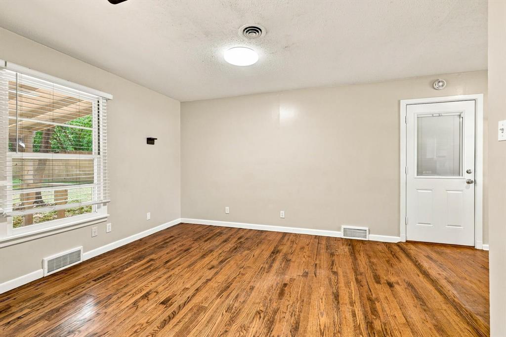 Wood-finish flooring, multi-pane window with horizontal blinds, and a white exterior door featuring a glass inset