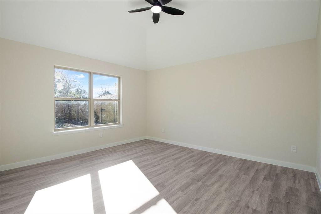Vaulted ceiling with a ceiling fan, light-toned walls, and wood-finish flooring