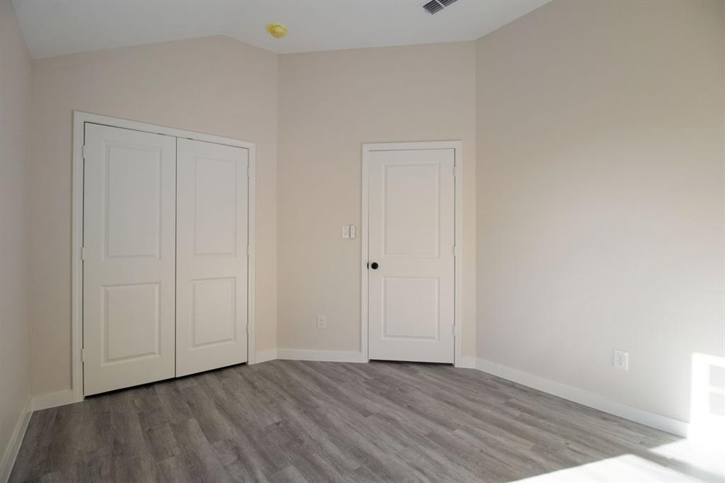 Vaulted ceiling, two-panel interior doors, light gray wood-finish flooring, and crisp white baseboards